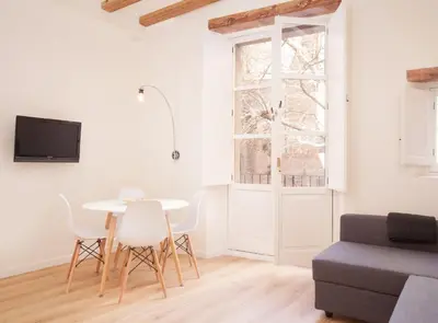 a living room with a table and chairs and a window at Alsina · Historical center - Barrio Gótico in Barcelona
