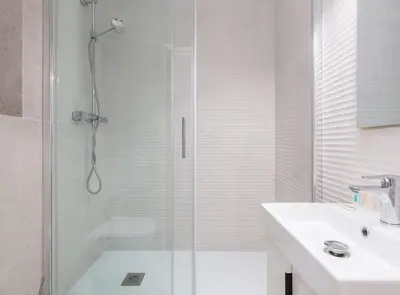 a white bathroom with a shower and a sink at Spacious doubleroom apartment at Sants in Barcelona