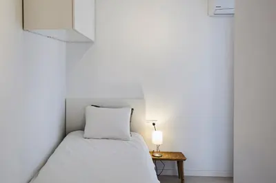 a small bedroom with a bed and a table at Sunny Beachfront Escape in Castelldefels