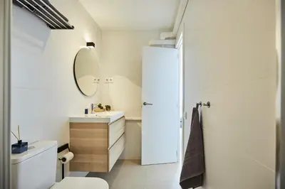 a bathroom with a white toilet and a mirror at Sunny Beachfront Escape in Castelldefels