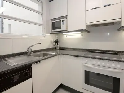 a white kitchen with a sink and a microwave at Apartment Vila Olímpica- Sant Martí - Sardenya by Interhome in Barcelona