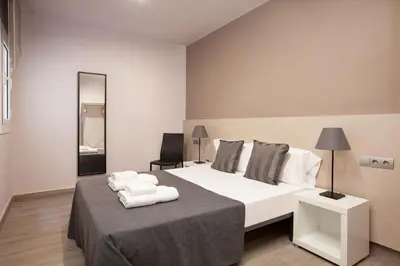 a bedroom with a large white bed and a chair at EasySleep Eixample in Barcelona