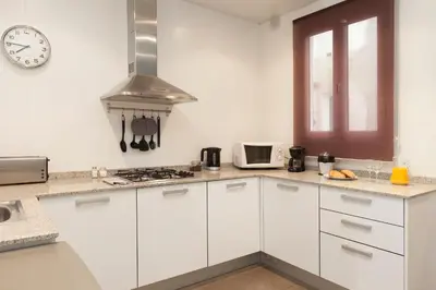 a kitchen with white cabinets and a clock on the wall at EasySleep Gaudi Terrace in Barcelona