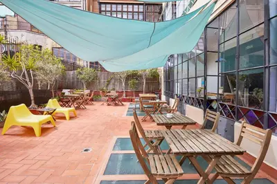 a patio with wooden tables and chairs on a building at Ella Hostel Gran Vía in Barcelona