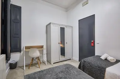 a bedroom with two beds and a desk and a chair at Ella Hostel Gran Vía in Barcelona