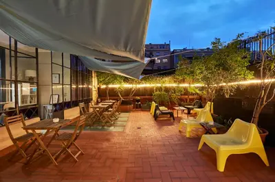 a rooftop patio with tables and chairs and lights at Ella Hostel Gran Vía in Barcelona