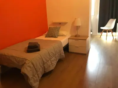 a bedroom with two beds and a lamp and a chair at Paraiso Hostel in Barcelona