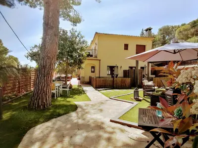 a backyard with a table and an umbrella and a tree at Cal Músic B&B in Premia de Dalt