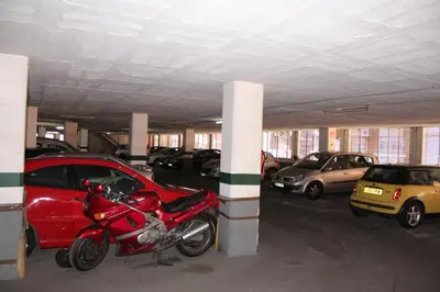 a parking garage with a red motorcycle parked next to cars at Natura Fira Barcelona in Hospitalet de Llobregat