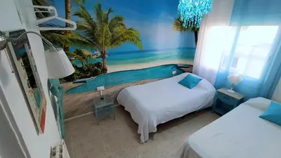 a bedroom with two beds and a mural of a beach at Hawaii Fira Barcelona in Hospitalet de Llobregat
