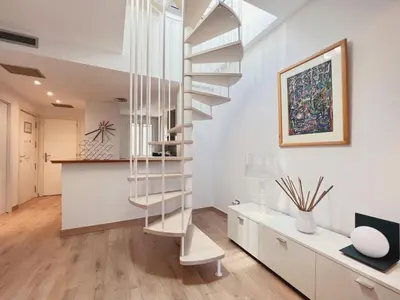 a spiral staircase in a white living room with a desk at Stay U-nique Apartments Urquinaona II in Barcelona