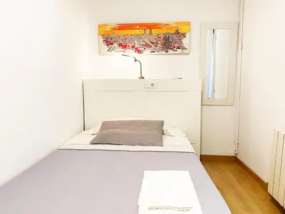 a small bedroom with a bed with a white headboard at Hostal Portugal in Barcelona