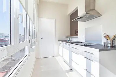 a kitchen with white cabinets and a large window at Central and Spacious Family Apartment in Barcelona