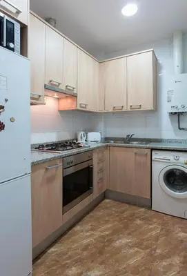 a kitchen with wooden cabinets and a white appliance at Cozy Flat With Unbeatable Views to Sagrada Familia in Barcelona