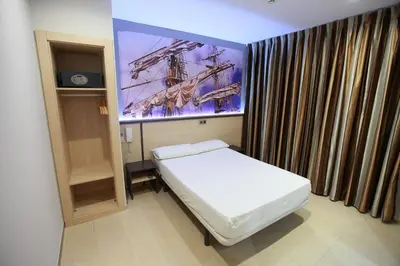 a small room with a bed and a large screen at Hostal Las Flores Ramblas in Barcelona