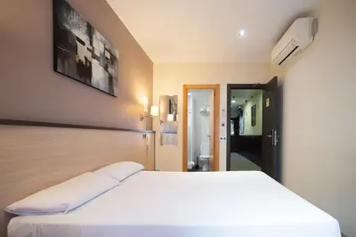 a bedroom with a white bed and a bathroom at Hostal Las Flores Ramblas in Barcelona