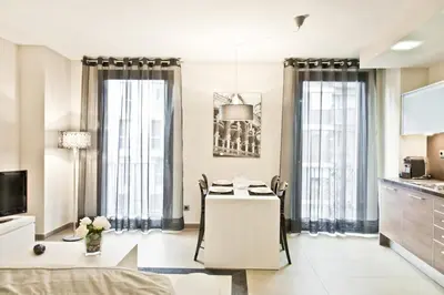 a living room with a table and a kitchen with windows at Up Suites BCN in Barcelona