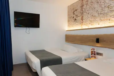 a hotel room with two beds and a flat screen tv at Hostal Paris in Barcelona