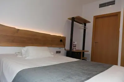 a bedroom with a large white bed with a wooden headboard at Hostal Paris in Barcelona