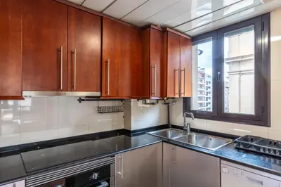 a kitchen with wooden cabinets and a sink and a window at Céntrico apartamento con terraza in Barcelona