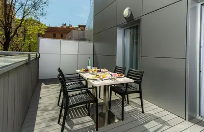 a table on a balcony with chairs and food on it at Leonardo Boutique Hotel Barcelona Sagrada Familia in Barcelona