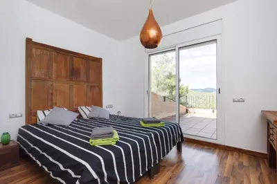 a bedroom with a bed and a large window at HHBCN Can Surià in Olivella