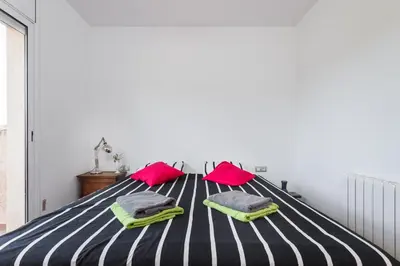a bedroom with a striped bed with pink and green pillows at HHBCN Can Surià in Olivella