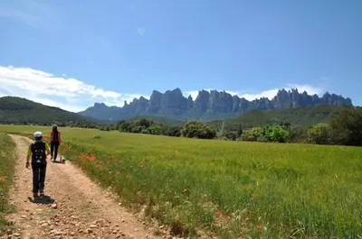 two people walking down a dirt road in a field at Montserrat La Calsina in Monistrol