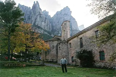 a man standing in front of a building with mountains in the background at Montserrat La Calsina in Monistrol