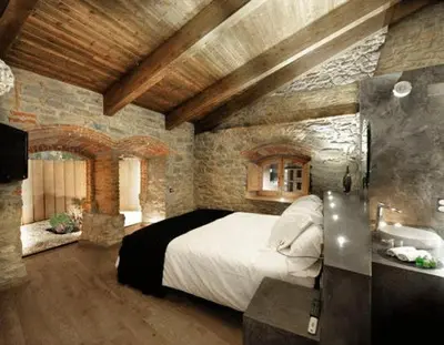 a bedroom with a large bed and a stone wall at Fonda La Masia Del Sola in Monistrol de Calders