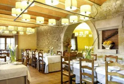 a restaurant with white tables and chairs and a large room at Fonda La Masia Del Sola in Monistrol de Calders