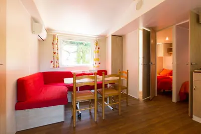 a living room with a red couch and a table at Camping Bungalows El Far in Calella