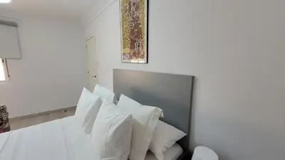 a bedroom with a white bed with white pillows at APARTAMENTS B O D CoLLBLANC in Hospitalet de Llobregat