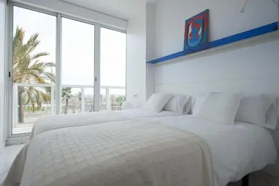 a white bedroom with two beds and a window at You Stylish Beach Apartments in Barcelona
