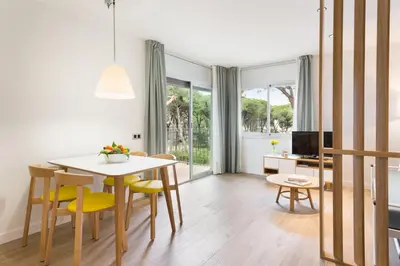 a living room with a table and chairs and a television at Apartamentos Porta Coeli in Castelldefels