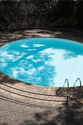 a swimming pool with a shadow of a tree in it at Apartamentos Porta Coeli in Castelldefels