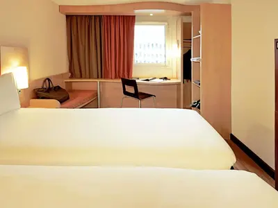 a bed in a room with a red window at Ibis Barcelona Centro (Sagrada Familia) in Barcelona
