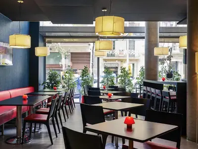 a restaurant with tables and chairs and a kitchen at Ibis Barcelona Centro (Sagrada Familia) in Barcelona