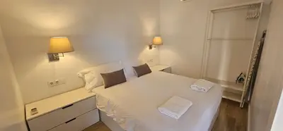 a small bedroom with a white bed with two pillows at Apartamento Playa Mar in Castelldefels
