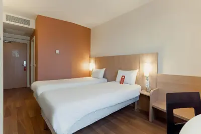 a hotel room with two beds and a window at Ibis Barcelona Mollet in Mollet del Vallès