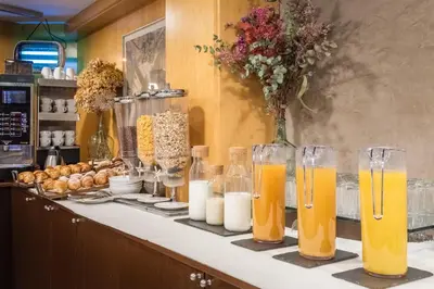 a counter with glasses of orange juice and other drinks at Hotel Madanis Liceo in Hospitalet de Llobregat