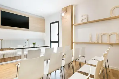 a dining room with white chairs and a flat screen tv at Hotel Acta Laumon in Barcelona