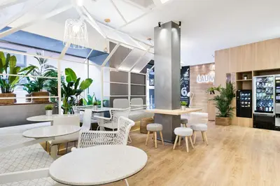 a restaurant with white chairs and tables and plants at Hotel Acta Laumon in Barcelona