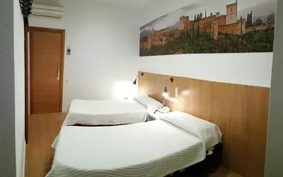 two beds in a room with a painting on the wall at Hostal Restaurante Cornella in Cornellà de Llobregat