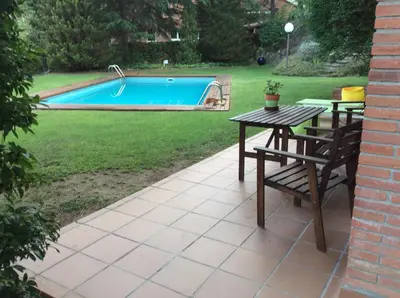 a patio with a table and chairs next to a pool at apartamento aislado jardín y piscina in Sant Andreu de Llavaneres