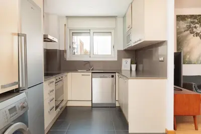 a small kitchen with white cabinets and a window at Mar Bella Beach Apartments in Barcelona