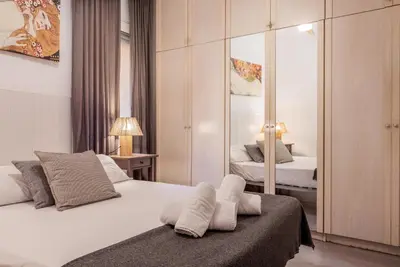 a bedroom with a bed with white sheets and a mirror at Portal Del Angel Barcelona Apartment in Barcelona