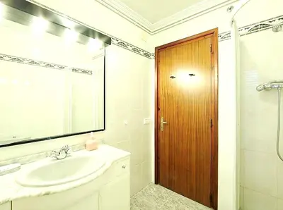 a bathroom with a sink and a wooden door at Spacious Apartment in Canyelles with Private Pool in Canyelles