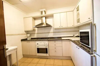 a kitchen with white cabinets and a stove top oven at Spacious Apartment in Canyelles with Private Pool in Canyelles