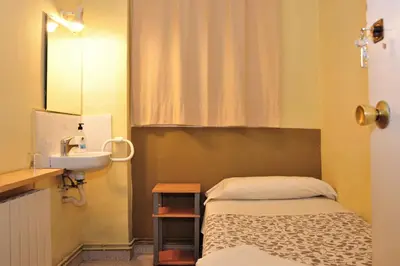 a small bathroom with a bed and a sink at Hostal Bejar in Barcelona